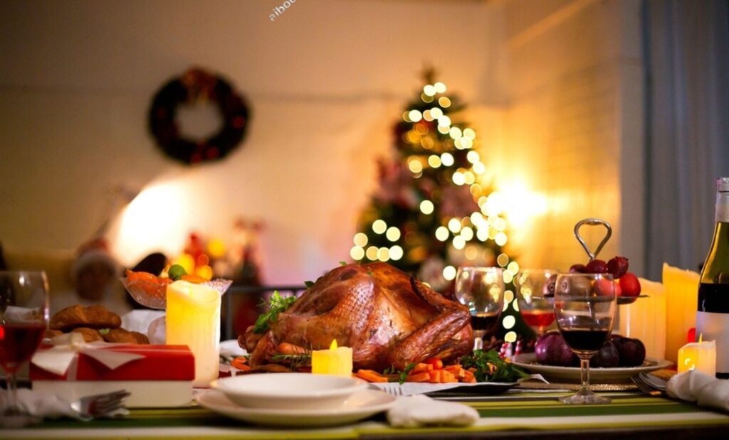 A festive Christmas dinner featuring a beautifully roasted turkey, surrounded by a decorated Christmas tree.