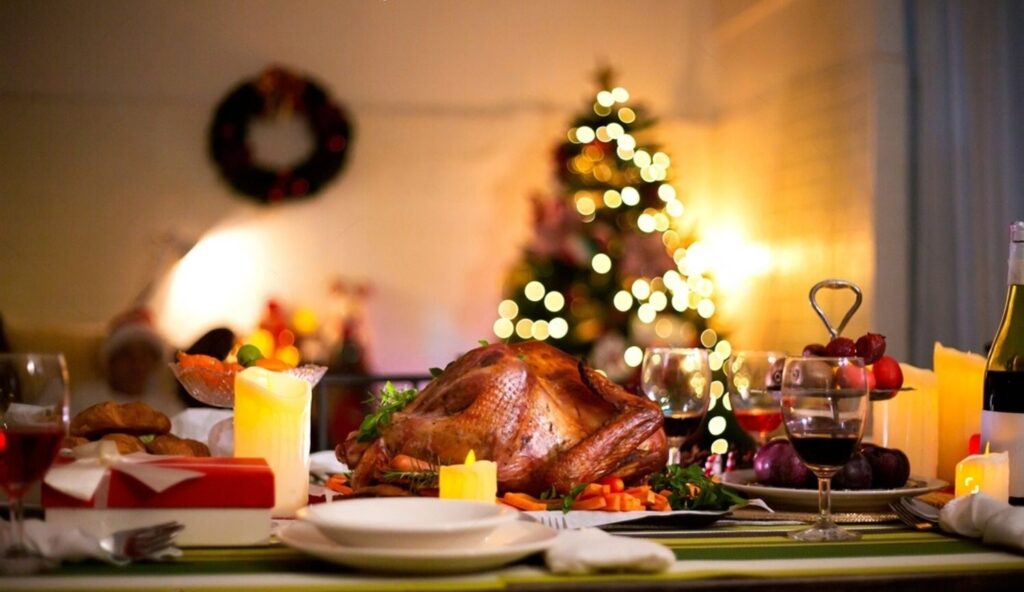 A festive Christmas dinner featuring a beautifully roasted turkey, surrounded by a decorated Christmas tree.